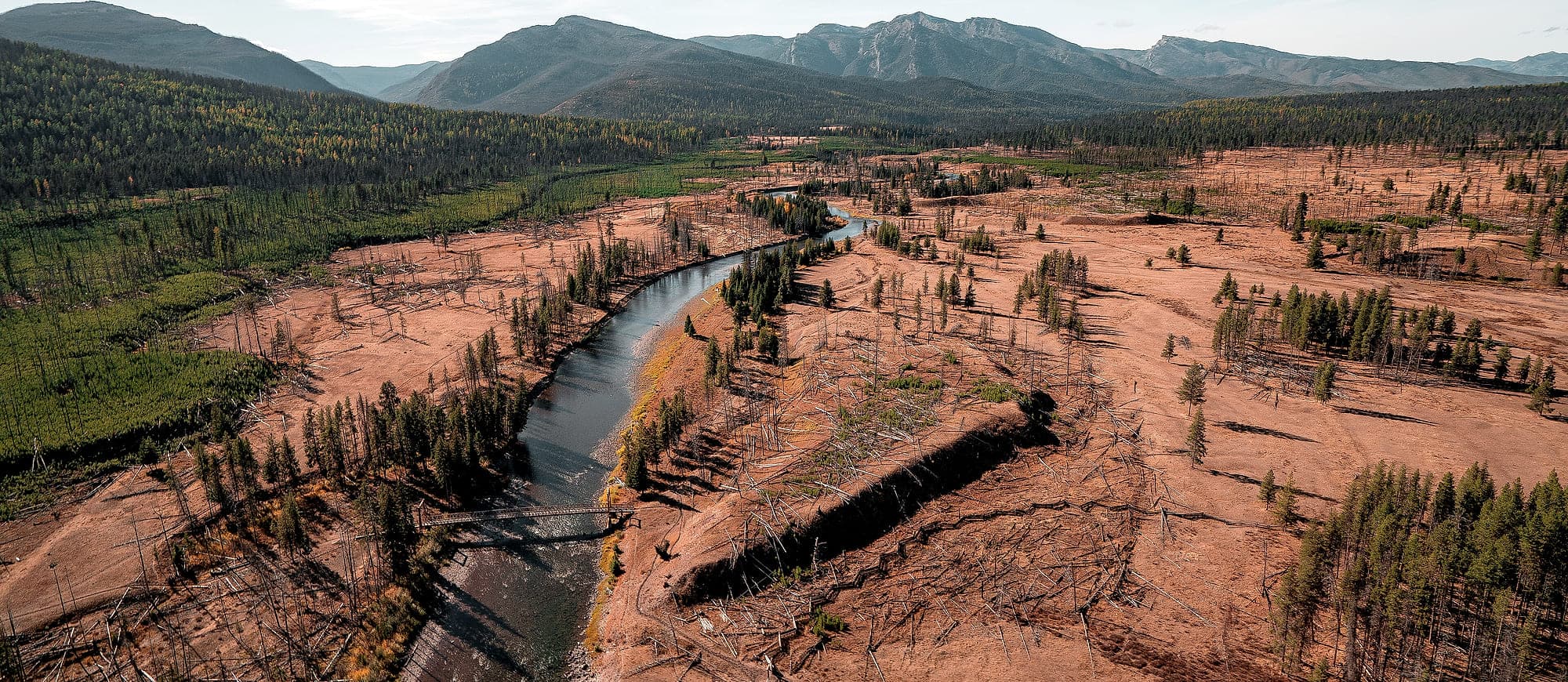 A creek running through open ground stripped of timber, seen from the air